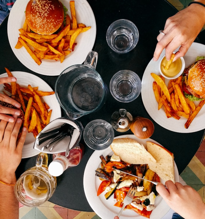 Top down image of friends eating food with burgers and water on the table. 