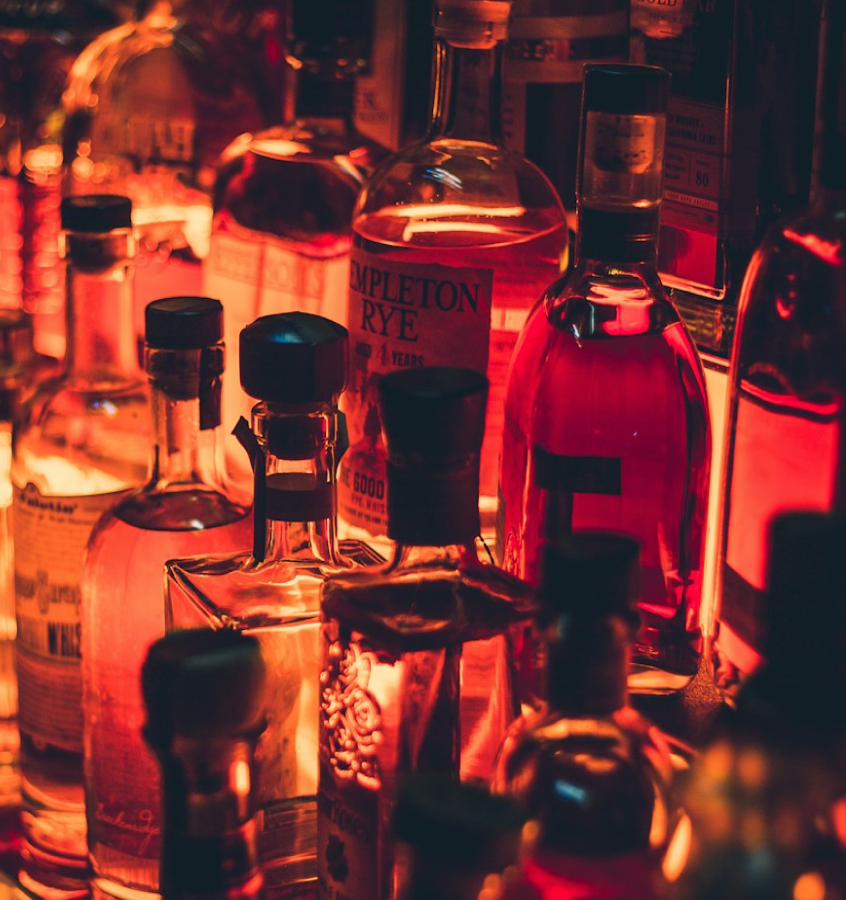 Close up of bottles of whiskey on a bar with red lighting.