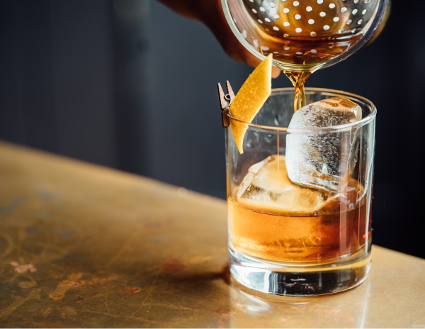 Image of someone pouring a glass of whiskey over ice